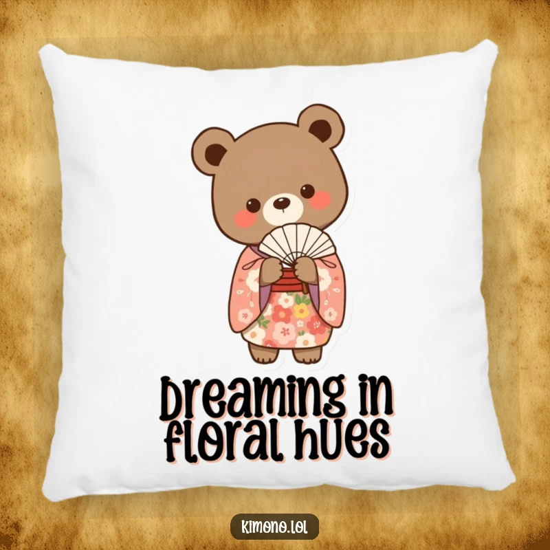 Funny small bear in a floral kimono gracefully holding a delicate fan on a soft pillow.